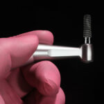 a single dental implant with a tool being used to hold it up